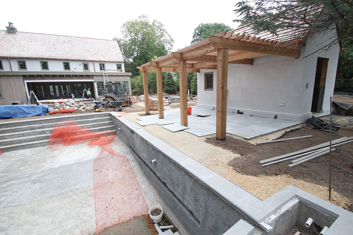 Installation of the dry laid Laurel tumbled edge Sandstone patio under the cedar pergola side of the pool house